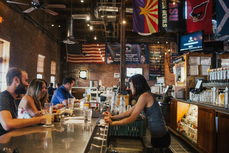 Woman wearing gray tank top in bar counter attending costumers